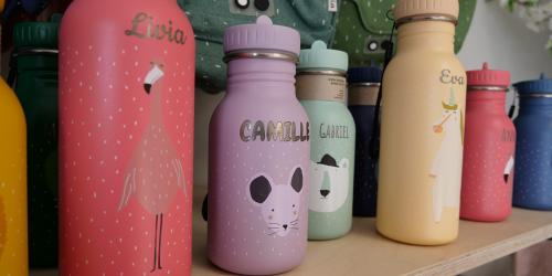 Colorful personalized water bottles with engraved names and playful animal illustrations on display