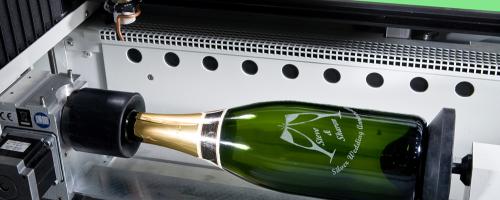 Champagne bottle engraving mounted on a rotary axis inside a CO2 laser machine